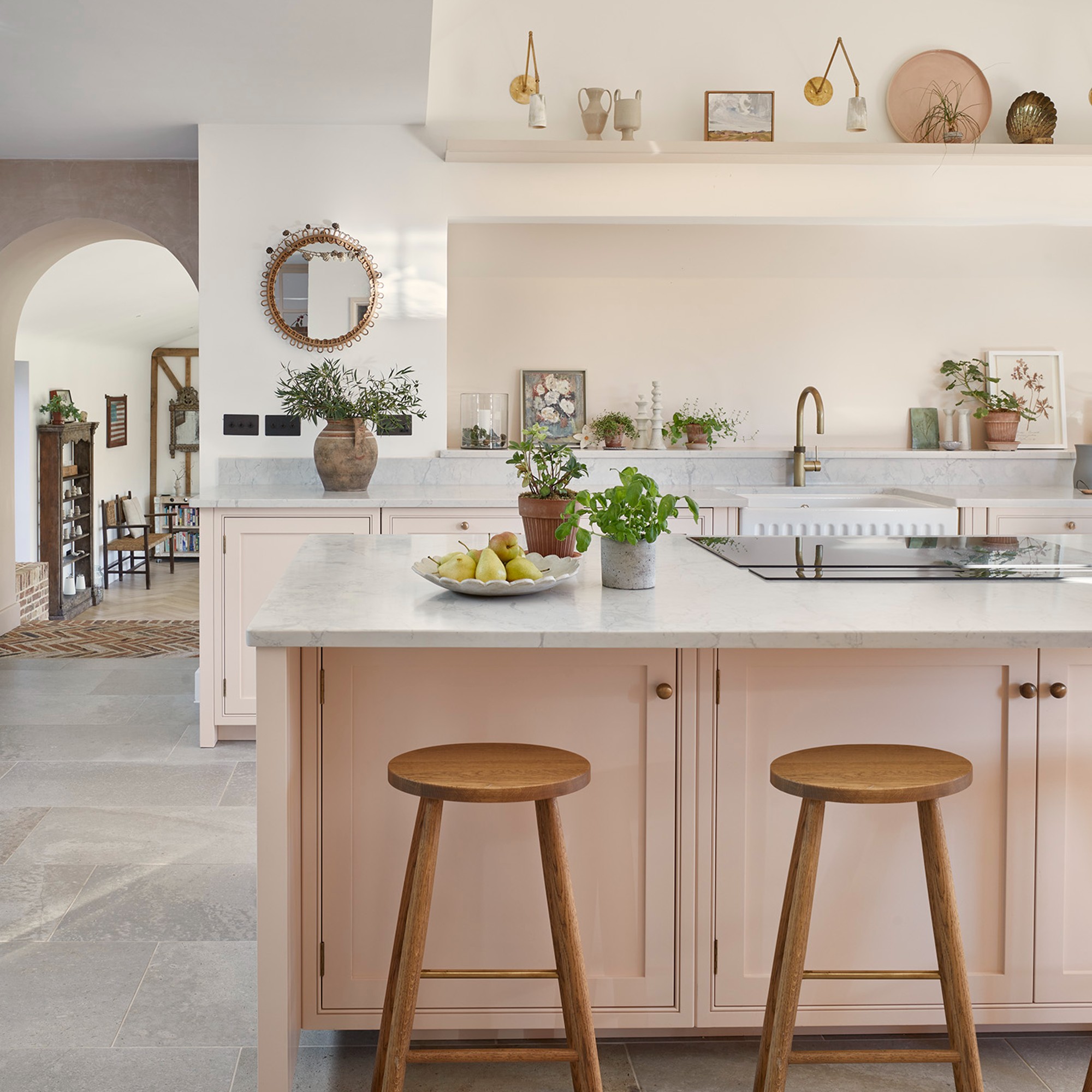 A light pink kitchen with a kitchen island and decorative objects