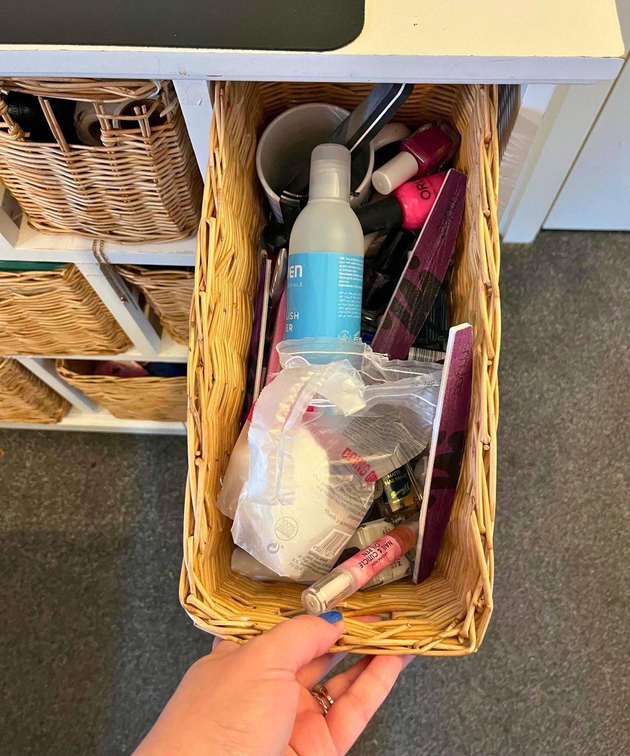 Nail drawer before. Wicket drawer pulled open by my hand showing a jumble of cotton pads, nail polish, nail files and a blue bottle of acetone