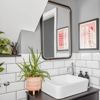 Small washroom with grey walls, metro tiles, mirror and sink
