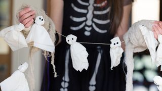 Halloween traditions illustrated by girl holding ghosts craft