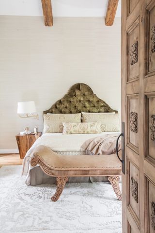 master bedroom with velvet buttonback headboard, leather bench and neutral color scheme