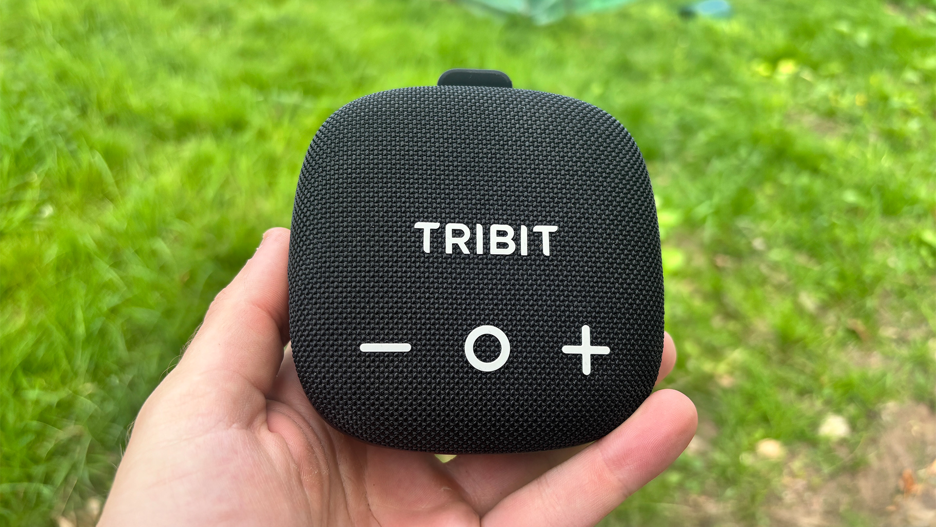 Tribit Stormbox Micro 3 Bluetooth speaker held in hand above green lawn
