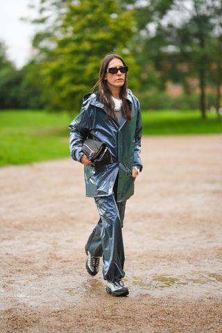 woman wearing a blue rain coat, blue pants, and boots