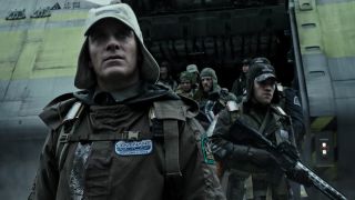 Scene from the movie Alien: Covenant. A group clad in military gear carrying futuristic weapons.