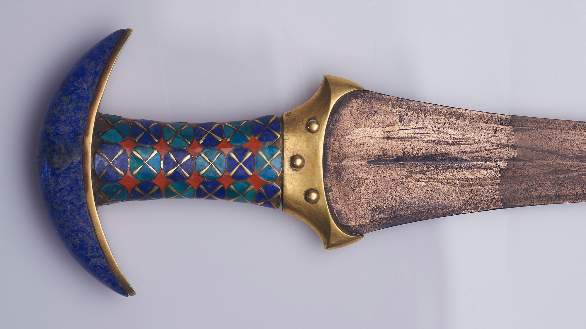 A close up of a blue and brown dagger against a white background