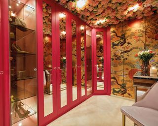 A magenta pink walk in wardrobe with textured floral ceiling, and oriental wallpaper