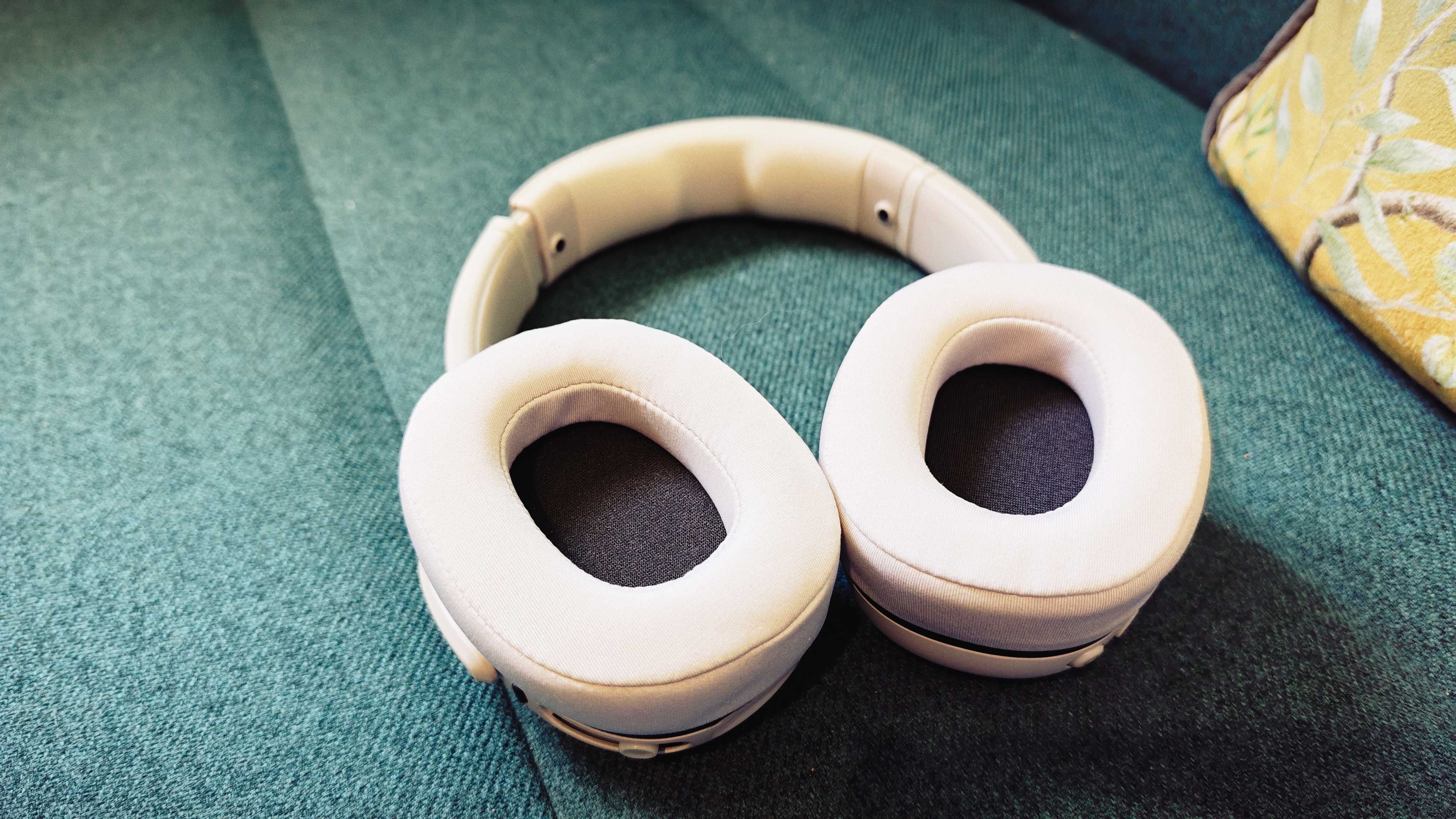A white pair of Skullcandy Crusher 540 Active headphones on a green sofa