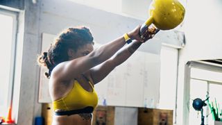 Woman performs kettlebell swing in gym