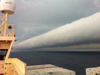 A roll cloud, associated with thunderstorm downdrafts and strange sea winds, tumbles across the sky off the coast of Brazil. Roll clouds are rare and harmless, though ominous-looking.
