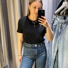 Woman in dressing room wears black t-shirt, jeans