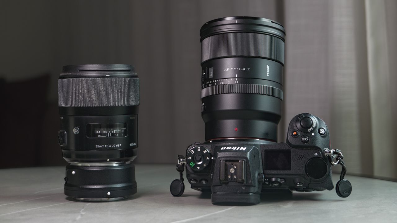 Viltrox AF 35mm F1.4 Pro lens attached to a Nikon mirrorless camera, alongside the Sigma 35mm f1/.4 DG Art lens with Nikon F to Z-mount adapter, on a white marble table