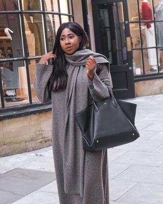 @_loissterling wears a knitted dress with a scarf and a large leather tote bag