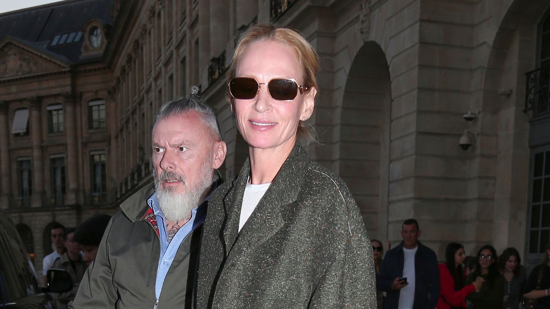 Uma Thurman steps outside in Paris wearing straight leg blue jeans with a grey blazer and navy loafers.