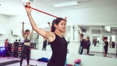 Woman in fitness studio holding pole above her head