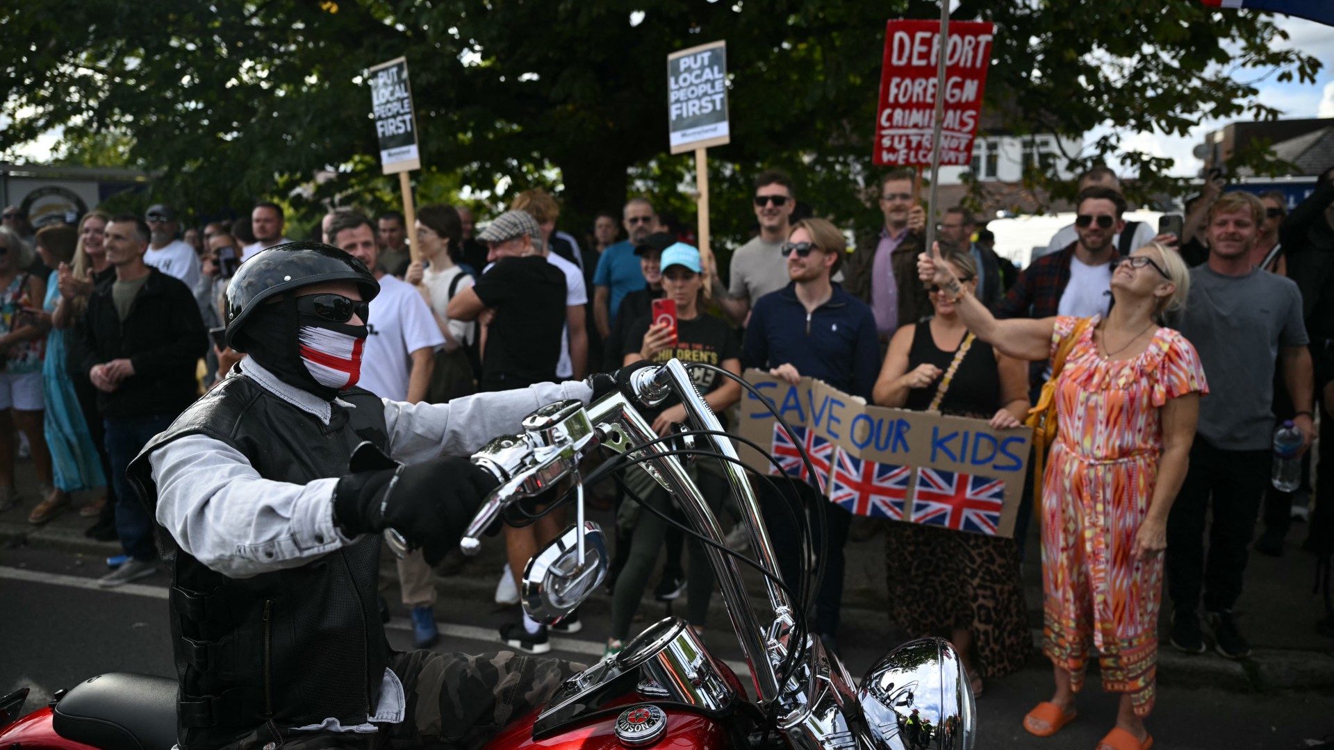 Protesters with placards line the pavement outside The Bell Hotel in Epping, Essex