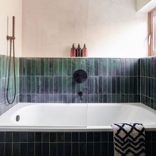 Navy tiled bathroom and bathtub, shower screen and patterned towel