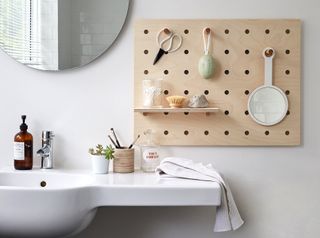 Peg board storage in a white bathroom