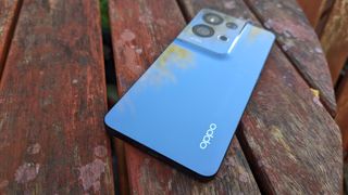 An Oppo Reno 8 Pro smartphone sitting on a rustic table