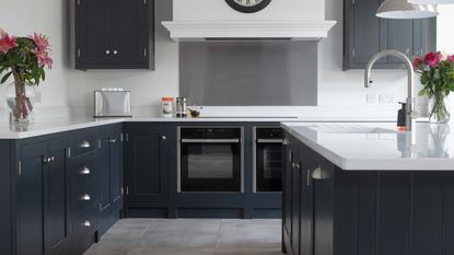 modern kitchen with dark cabinetry, white worktops and double oven