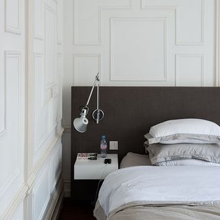 bedroom with white wall bed with cushions and wall lamp