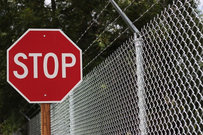 A stop sign and barbed wire fence.