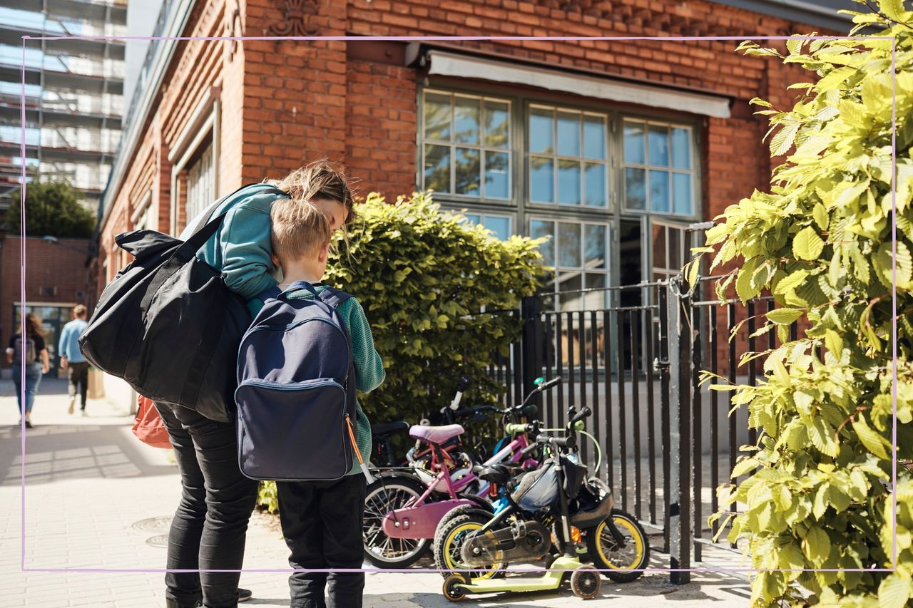 A woman and a young boy standing close together outside school gates