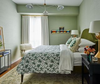bedroom with green textured walls and patterned bedcover