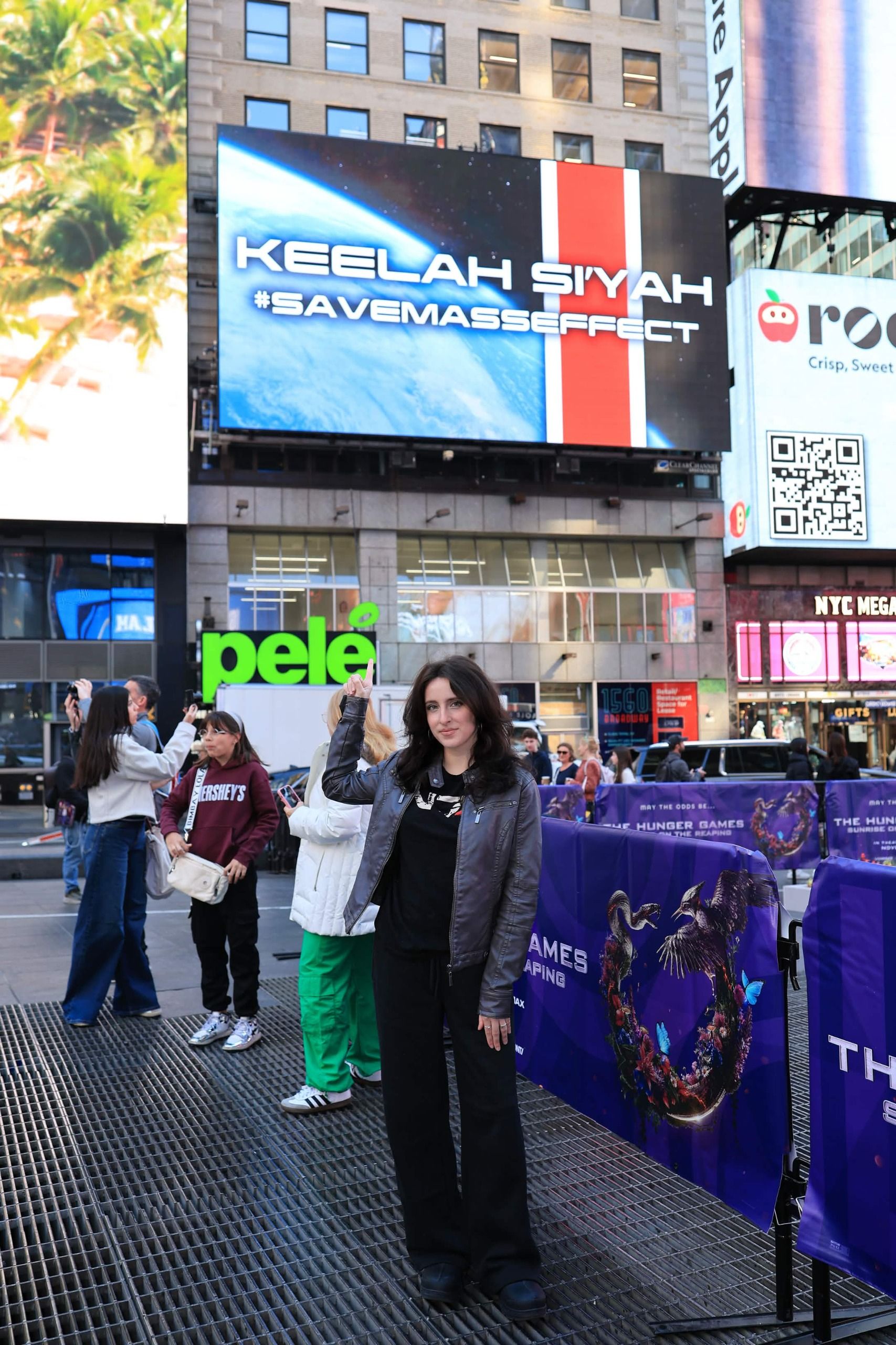 Mer from the We Are Mass Effect stands and points to billboard