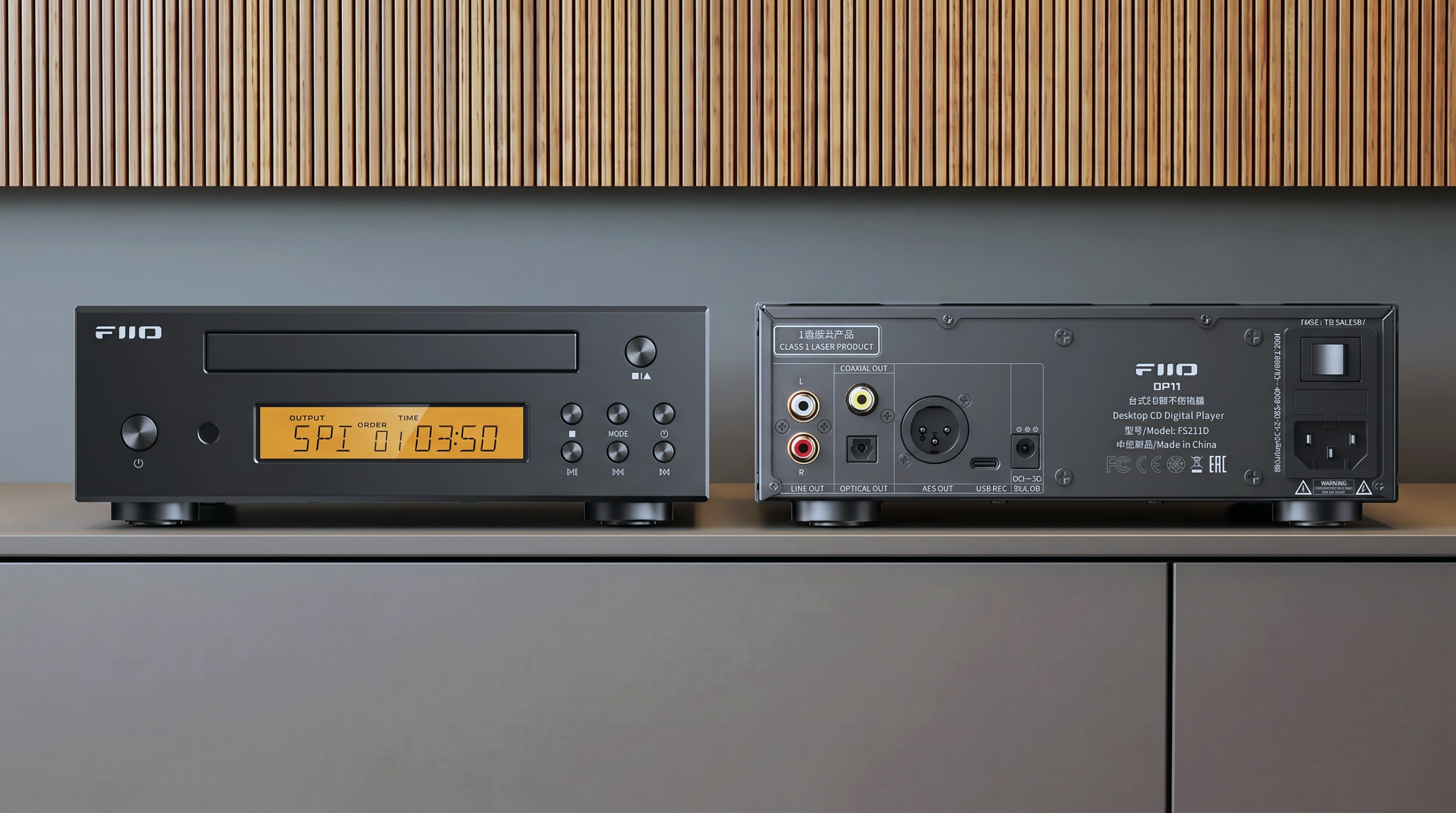 FiiO DP11 in black on a hi-fi table, with wooden panelling in the background