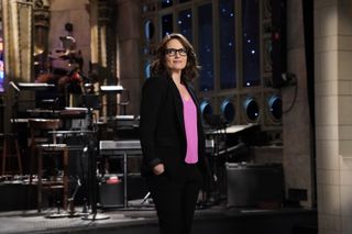 Tina Fey wearing a blazer and pink shirt on the snl stage