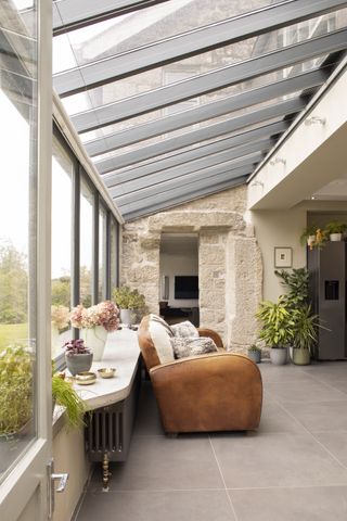 grey small conservatory with sofa and exposed stone wall