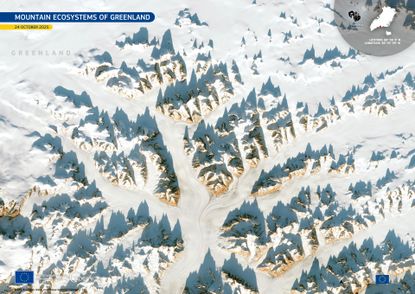 A series of snow-covered mountain peaks jut out against a white landscape in an image seen from space