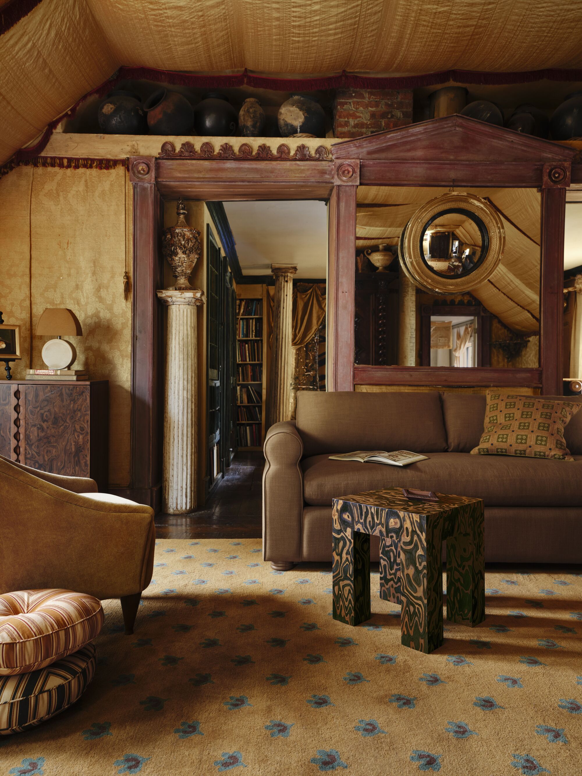 a room filled with dark timber features, a yellow rug, striped cushions, a timber side table, brown sofa, and large mirror