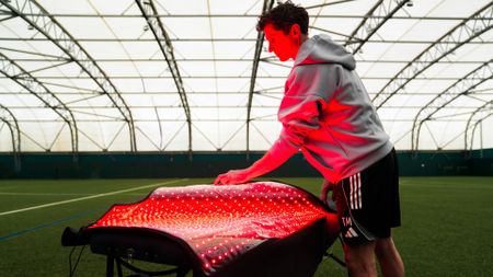 Member of Fulham FC opening up the Bon Charge red light therapy blanket on the training pitch