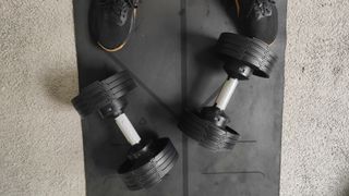 Closeup of the BLK BOX Adjustable Dumbbell on a carpeted floor