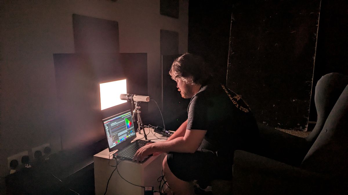 Samsung S95F OLED TV with testing equipment attached and man testing brightness