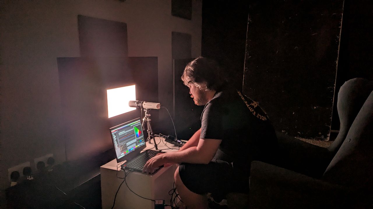 Samsung S95F OLED TV with testing equipment attached and man testing brightness