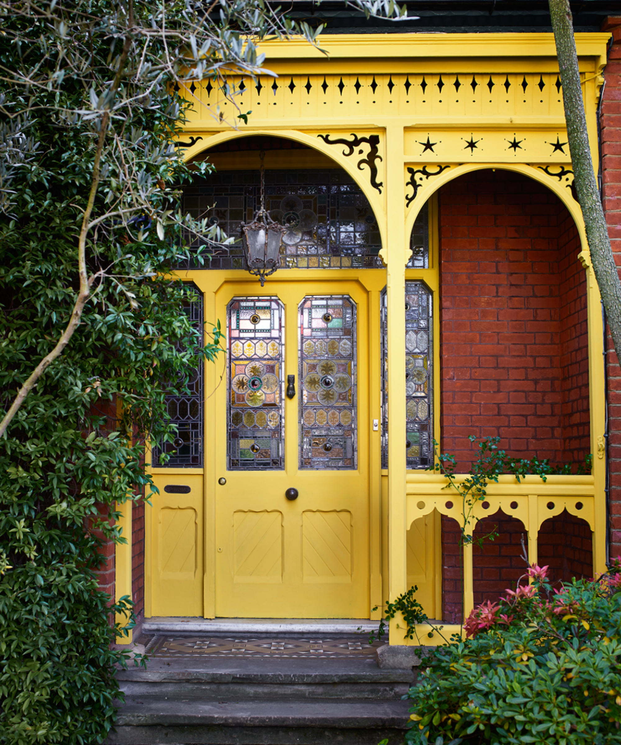 yellow metal porch with fretwork detailing over front door painted in same yellow