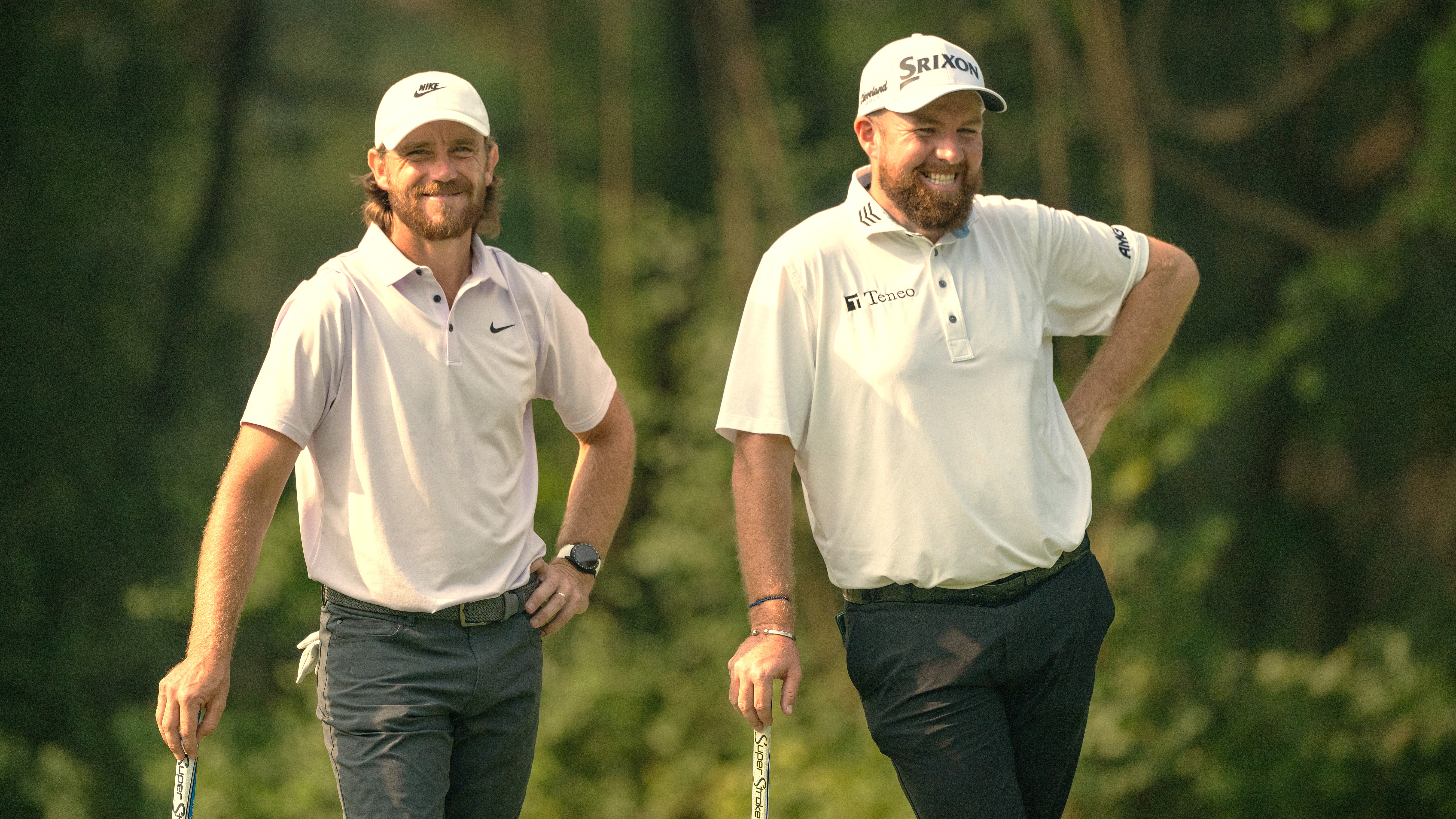 Tommy Fleetwood and Shane Lowry standing together leaning on their putters