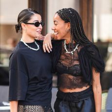 Two guests in black with bright glowy skin talking and laughing