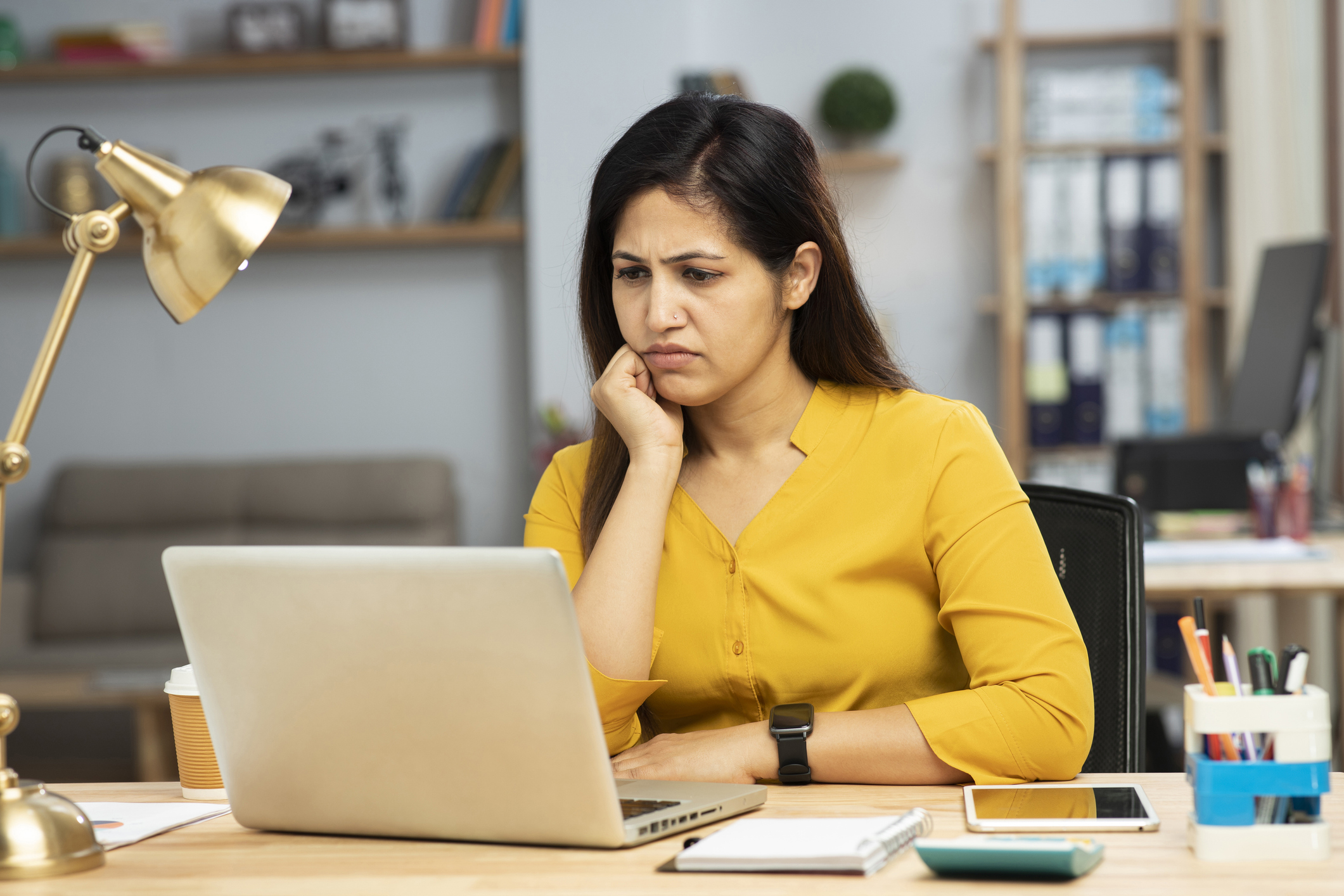 Young woman working in a modern office with laptop, notebook, lamp and calculator