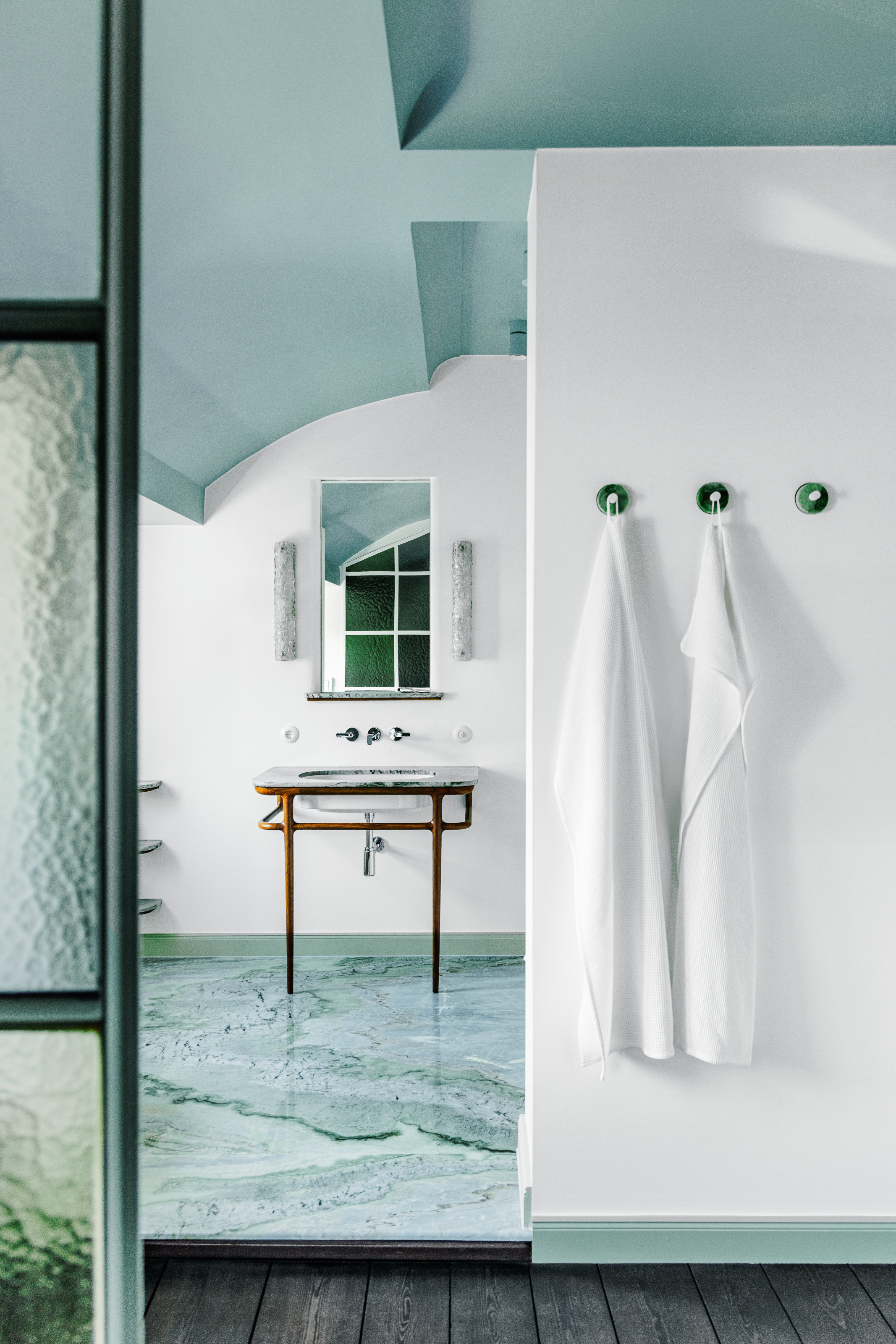 Blue bathroom with curved ceiling, stone floor and mint towel hooks