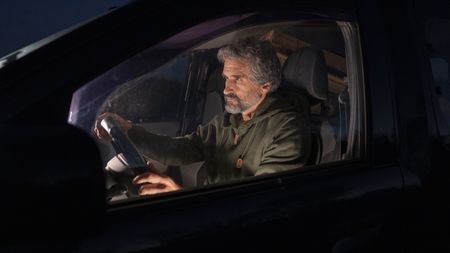 An older man driving at night isn't wearing a seat belt.