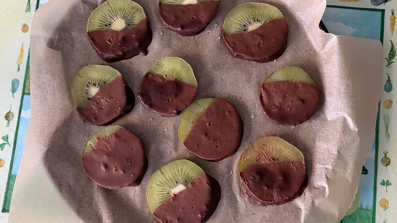A close up of kiwis coated in dried chocolate on a baking tray