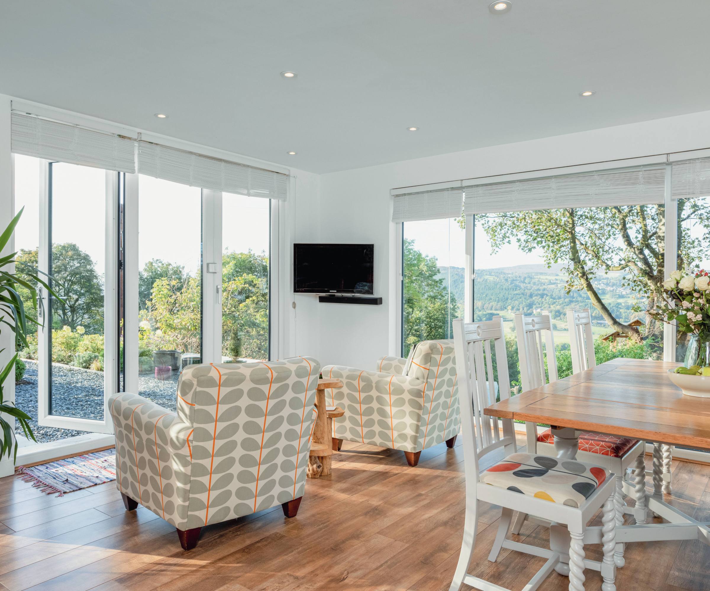 Living/dining room featuring full height windows and bifold doors with colourful chairs