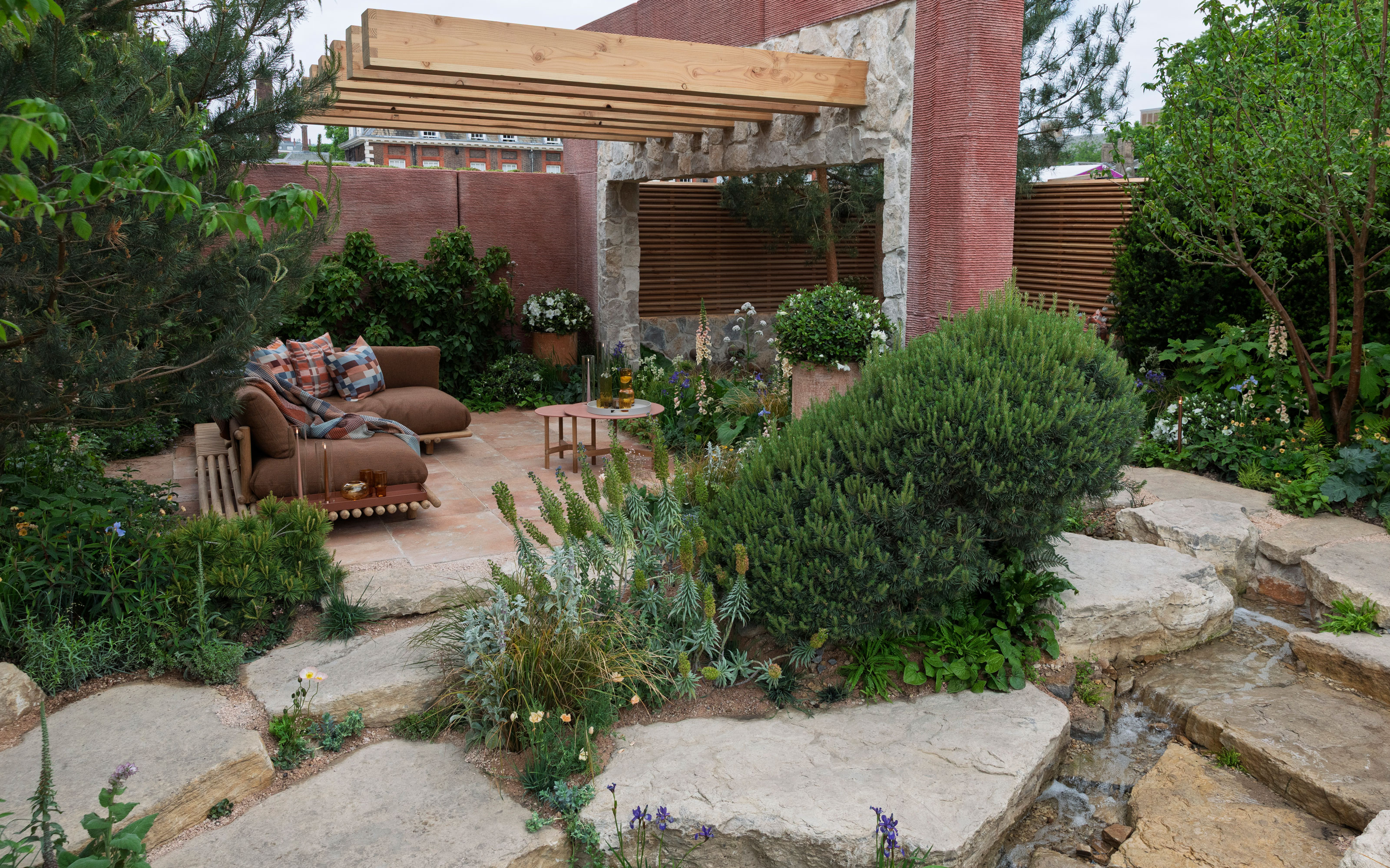 rock garden landscape with pergola, evergreen shrubs and garden furniture