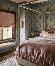 Colorful patterned bedroom with blue floral wallpaper, pink blind, pink bedding, wooden four-poster bed