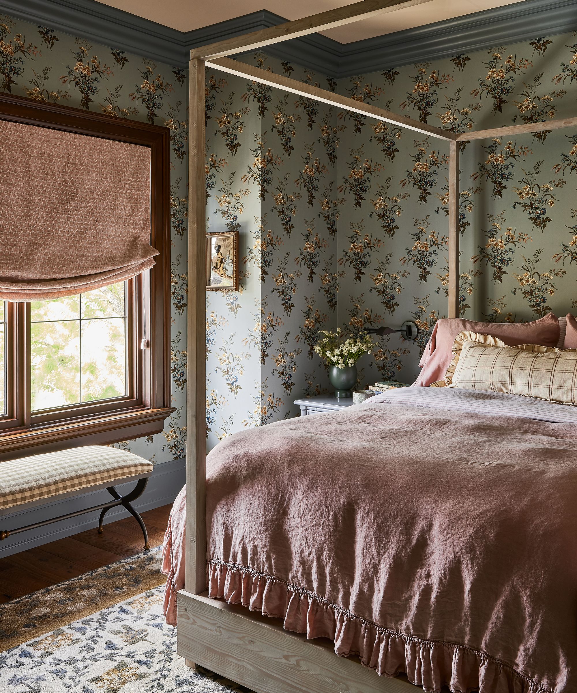 Colorful patterned bedroom with blue floral wallpaper, pink blind, pink bedding, wooden four-poster bed