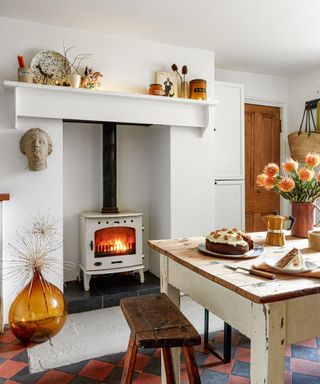 Kitchen fireplace styled for fall with a large amber glass bottle vase and dried flowers