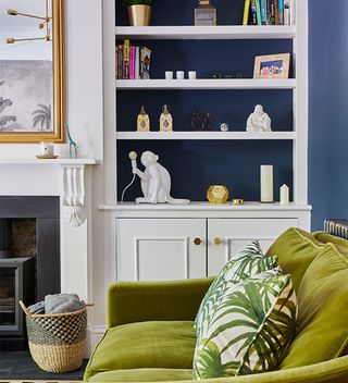 white living room with alcove shelves and blue painted wall with green sofa